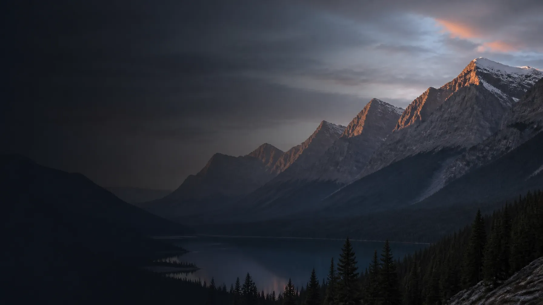 Scenic Canadian Rockies landscape with layered charcoal mountains and warm light on the distant ridges